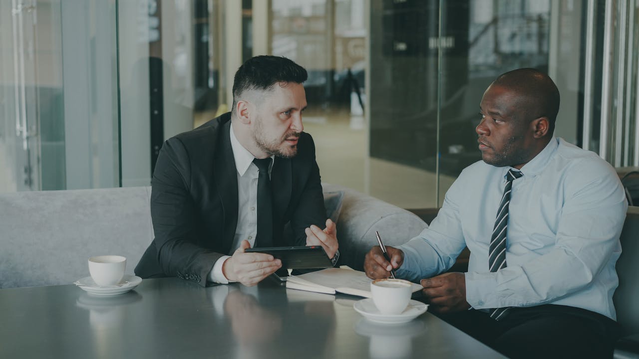 Two businessmen in discussion over coffee, brainstorming in a modern office setting.