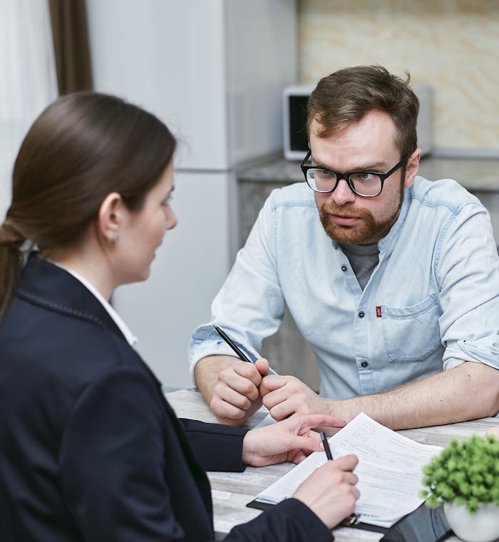 Two colleagues discussing work notes during a professional meeting indoors.